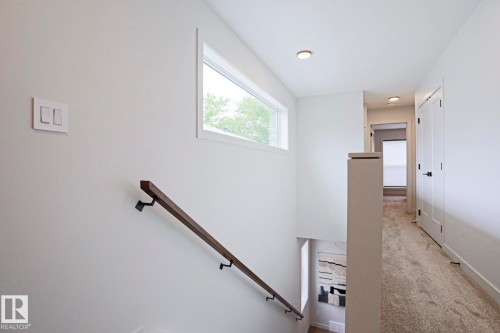 Upper-level hallway featuring a horizontal window, recessed lighting, and light-toned carpeting - 12842 121 Street, Edmonton, AB 