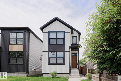 Modern two-story residence featuring a white vertical siding facade with black accents and a dark-pitched roof - 12842 121 Street, Edmonton, AB 