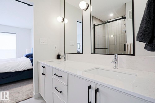 Dual vanity with integrated sinks, white cabinetry, chrome fixtures, and contemporary lighting - 12842 121 Street, Edmonton, AB 