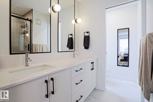 Dual sink vanity featuring white cabinetry, light-toned countertops, and matte black hardware - 12842 121 Street, Edmonton, AB 
