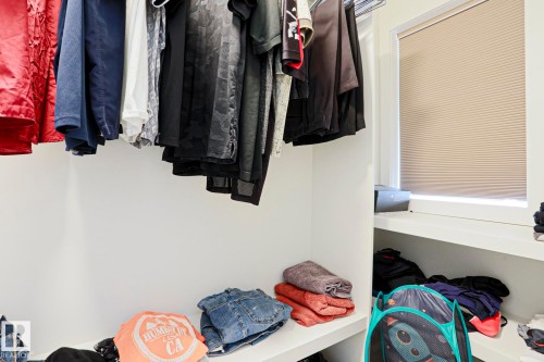 Integrated closet storage featuring white shelving, a full-width clothing rod, and a window with a cellular shade - 12842 121 Street, Edmonton, AB 