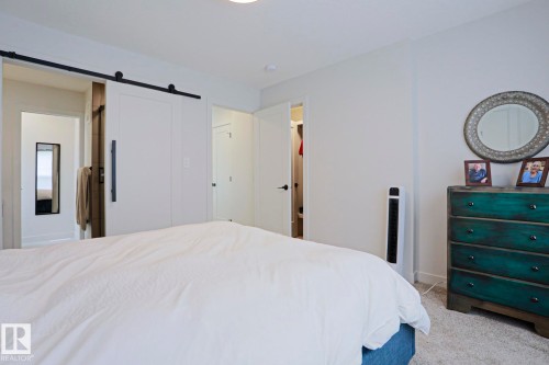 Bedroom featuring a contemporary barn door, bright white walls, recessed ceiling lighting, and light-colored carpet flooring - 12842 121 Street, Edmonton, AB 