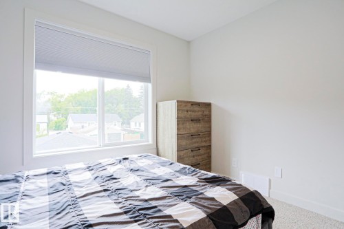 Carpeted room featuring a large window with white trim and a cellular shade - 12842 121 Street, Edmonton, AB 