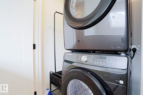 Dedicated laundry area featuring a stacked washer and dryer unit - 12842 121 Street, Edmonton, AB 