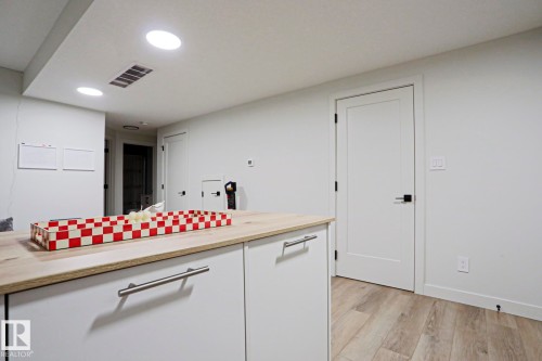 White cabinetry with stainless steel bar pulls and a light wood-finish countertop - 12842 121 Street, Edmonton, AB 