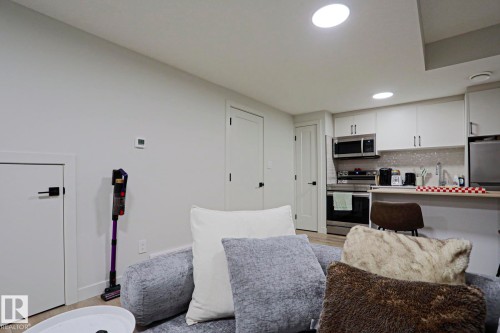 Contemporary kitchen featuring white cabinetry, stainless steel appliances, a tile backsplash, and recessed lighting - 12842 121 Street, Edmonton, AB 