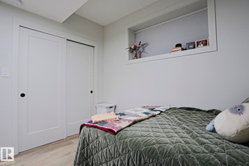 Bedroom featuring light wood-finish flooring, white walls, and a built-in recessed window ledge - 12842 121 Street, Edmonton, AB 
