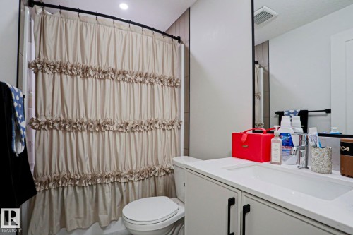 Bathroom featuring a single vanity with integrated sink, white countertop, and dark cabinet hardware - 12842 121 Street, Edmonton, AB 
