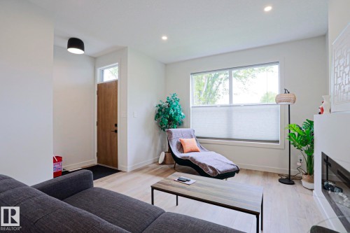 Bright living area featuring wood-finish flooring, recessed lighting, and a large window with privacy blinds - 12842 121 Street, Edmonton, AB 