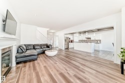 Open-concept living area with wood-finish flooring, a fireplace with a tiled surround, and a white mantel - 