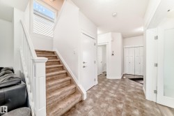 Carpeted staircase with white railing, tile flooring, white walls, white trim, and a window with blinds - 