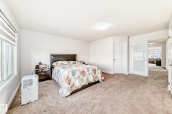 Spacious carpeted room featuring white walls, a large window with horizontal blinds, a white flush-mount ceiling light, and a white interior door with a paneled design - 