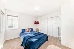 Bedroom featuring neutral-toned carpeting, white walls, and a ceiling-mounted light fixture - 
