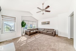 Spacious room featuring vaulted ceilings, a contemporary ceiling fan, and multiple windows providing ample ambient light - 
