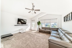 Living area featuring vaulted ceilings, a ceiling fan with integrated lighting, and carpet flooring - 