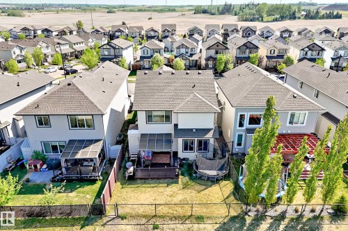Rear exterior featuring a covered deck, fenced yard with green space, and a mature tree line at the property boundary - 2812 12 Street, Edmonton, AB 