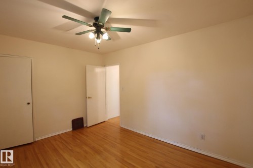 Room featuring wood-finish flooring, a ceiling fan with integrated lighting, and neutral wall paint - 11242 56 Street, Edmonton, AB 