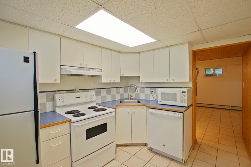 Kitchen featuring white cabinetry, a built-in dishwasher, an electric range, a stainless steel sink with a gooseneck faucet, and blue countertops - 11242 56 Street, Edmonton, AB 