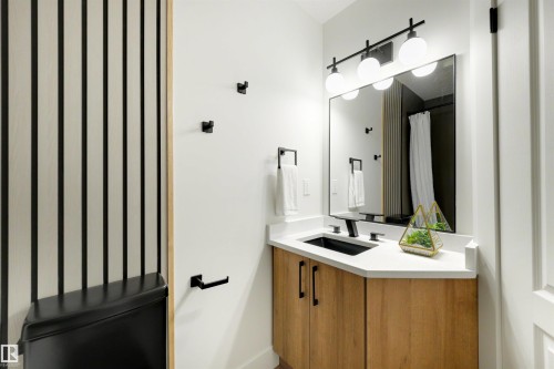 Bathroom featuring a light wood-finish vanity with a black rectangular basin and a white countertop - 12611 47 Street, Edmonton, AB 