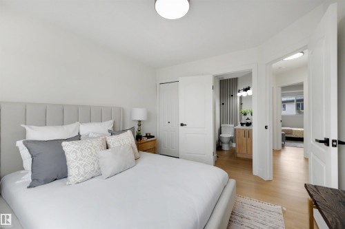 Bedroom featuring wood-finish flooring, a white paneled door, and a built-in closet with bifold doors - 12611 47 Street, Edmonton, AB 