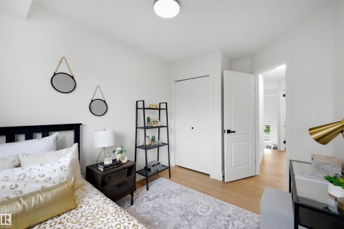 Bedroom featuring wood-finish flooring, a double-door closet with black hardware, and a white interior door - 12611 47 Street, Edmonton, AB 