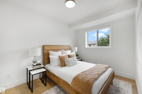 Light-filled bedroom featuring wood-finish flooring, a contemporary window, and crisp white walls - 12611 47 Street, Edmonton, AB 
