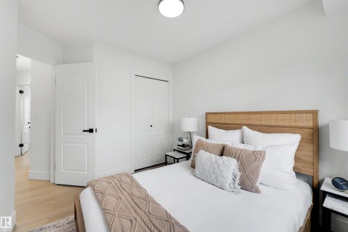 Bright interior space featuring light wood-finish flooring, a white paneled door with matte black hardware, and a closet with bi-fold doors - 12611 47 Street, Edmonton, AB 