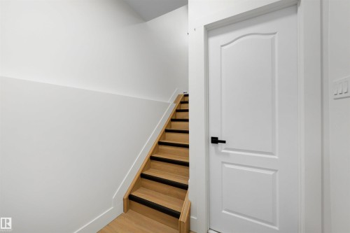 Natural wood-finish staircase with black tread accents and crisp white risers - 12611 47 Street, Edmonton, AB 