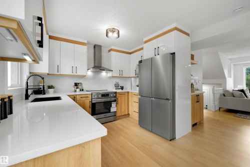 Modern kitchen featuring light wood-finish flooring, white countertops, and a stainless steel appliance suite - 12611 47 Street, Edmonton, AB 