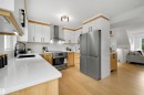 Modern kitchen featuring light wood-finish flooring, white countertops, and a stainless steel appliance suite - 12611 47 Street, Edmonton, AB 