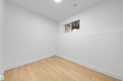 White painted walls with a small window, light wood-finish flooring, and recessed ceiling lighting - 