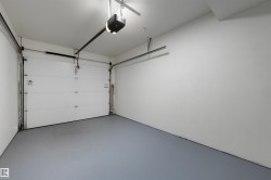 Spacious garage featuring a white overhead door, gray floor coating, white walls, and an overhead lighting fixture - 