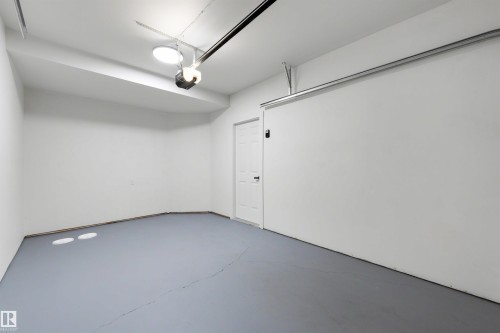 Spacious garage featuring light gray floor coating, white painted walls, and an overhead garage door opener - 12611 47 Street, Edmonton, AB 