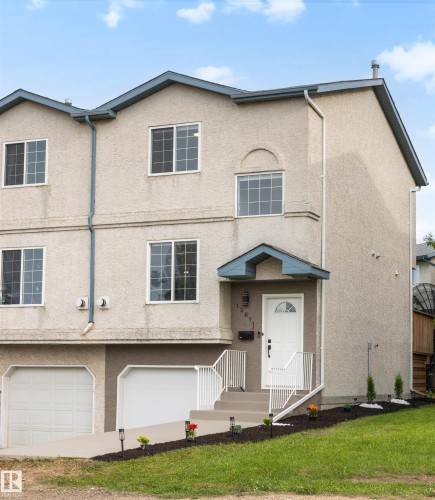 Multi-level stucco exterior featuring an integrated garage, covered front entry, and multiple windows - 12611 47 Street, Edmonton, AB 