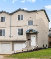 Multi-level stucco exterior featuring an integrated garage, covered front entry, and multiple windows - 