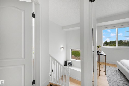 Upper-level landing featuring a white baluster railing and wood-finish flooring - 12611 47 Street, Edmonton, AB 