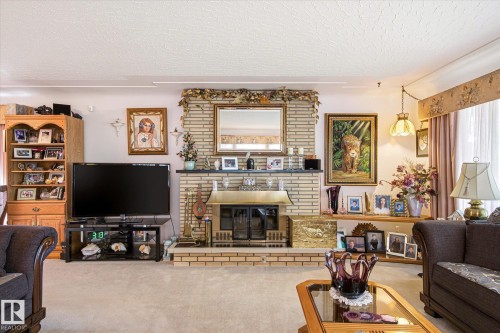 Living area featuring a brick fireplace with a brass firebox and mantel, flanked by built-in shelving and a wood-finish display cabinet - 9747 67 Avenue, Edmonton, AB 