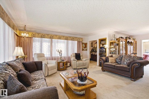 Spacious living area featuring neutral carpeting and textured ceiling - 9747 67 Avenue, Edmonton, AB 