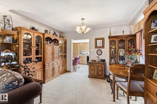 Carpeted living space featuring crown molding and a prominent ceiling light fixture - 9747 67 Avenue, Edmonton, AB 