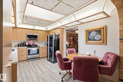 Kitchen featuring light wood-finish cabinetry, stainless steel appliances, a subway tile backsplash, and light wood-finish flooring - 9747 67 Avenue, Edmonton, AB 