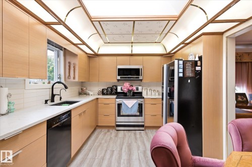 Contemporary kitchen featuring wood-finish cabinetry, light-toned countertops, and a white subway tile backsplash - 9747 67 Avenue, Edmonton, AB 