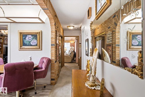 Exposed brick archway opening onto a hallway with carpet flooring and a round ceiling light - 9747 67 Avenue, Edmonton, AB 