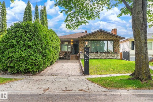 Stone facade residence featuring a prominent front window and an integrated front entry - 9747 67 Avenue, Edmonton, AB 