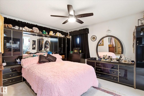 Spacious room featuring a ceiling fan with light fixture, mirrored wall-spanning cabinetry, and hard-surface flooring - 9747 67 Avenue, Edmonton, AB 