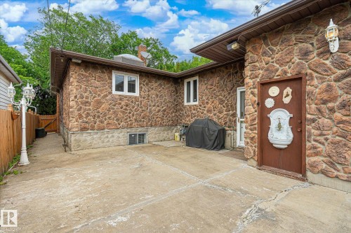 Stone veneer exterior with a concrete patio - 9747 67 Avenue, Edmonton, AB 