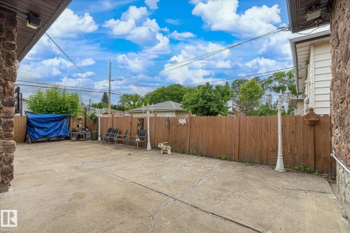 Expansive concrete patio area with a wood privacy fence - 9747 67 Avenue, Edmonton, AB 
