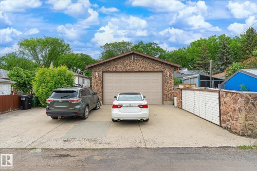 Stone-clad detached garage featuring a single overhead door and a concrete driveway - 9747 67 Avenue, Edmonton, AB 