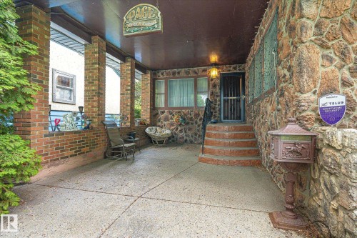 Stone and brick facade featuring a covered porch, concrete flooring, and an ornate metal mailbox - 9747 67 Avenue, Edmonton, AB 