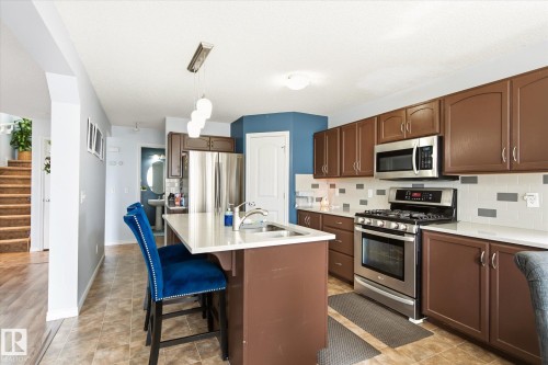 Kitchen featuring stainless steel appliances, brown cabinetry, and light countertops - 1744 61 Street, Edmonton, AB 