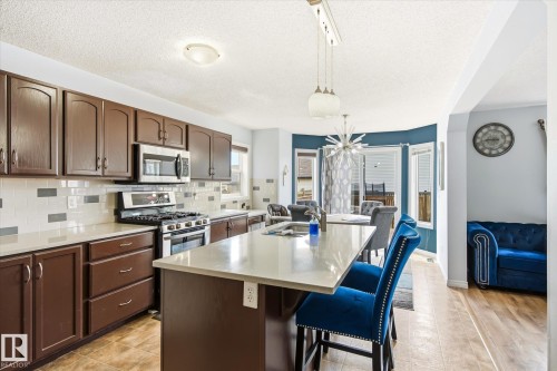 Kitchen featuring brown cabinetry, white countertops, and a subway tile backsplash - 1744 61 Street, Edmonton, AB 